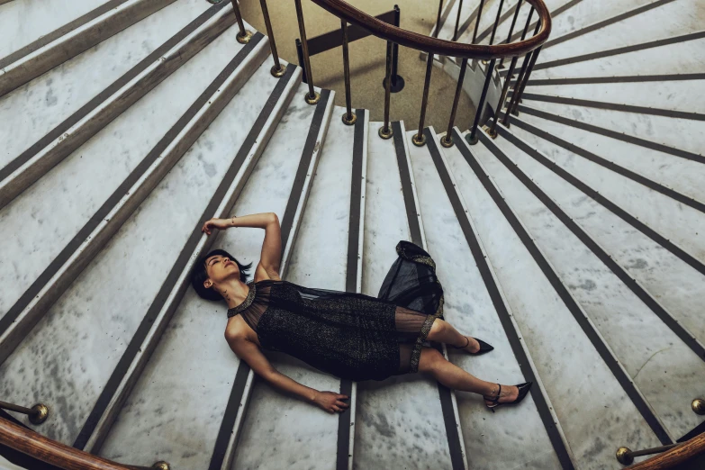 the young man is lying down on the floor near a spiral staircase