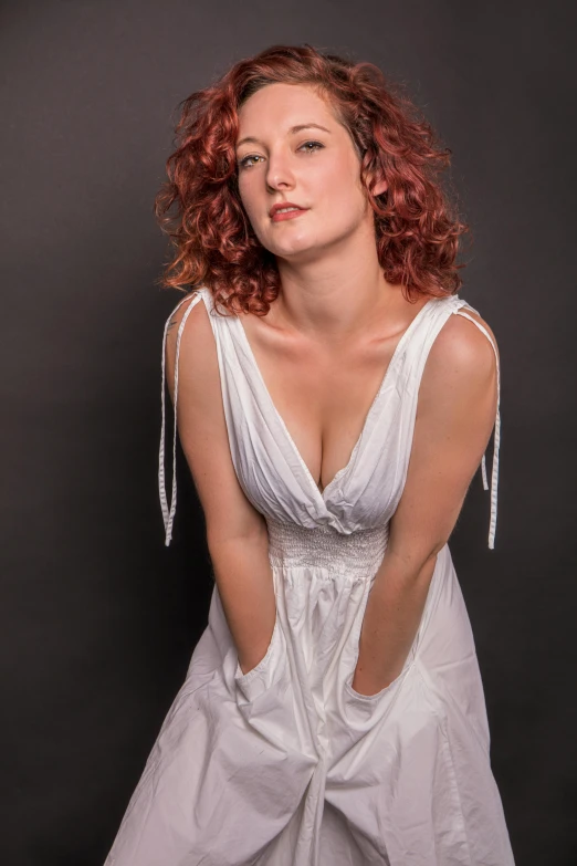 an attractive woman with red hair and a white dress