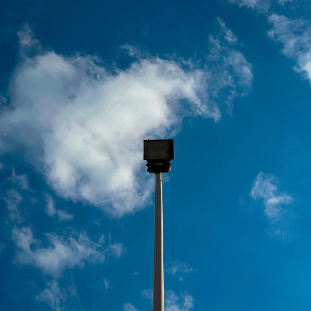 a street light in front of a blue sky with clouds