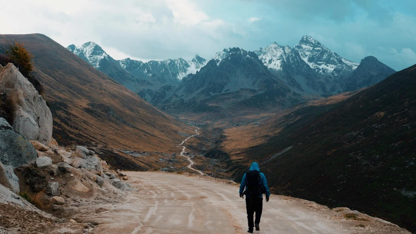 there is a man walking down the dirt road