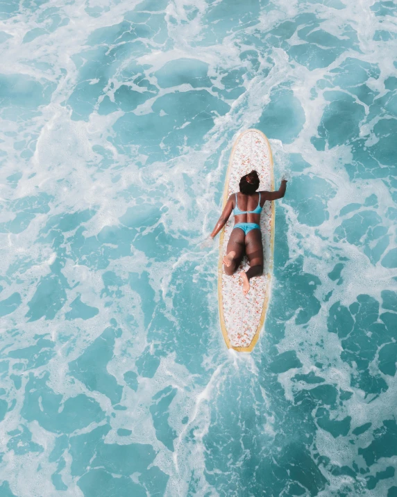 a woman is laying on her surfboard in the water