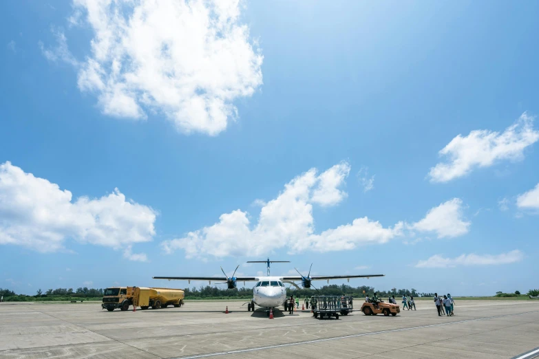 there is a small airplane on the runway and people are standing around it