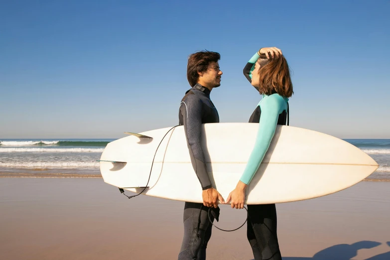 a woman and man with surfboards walking towards the ocean