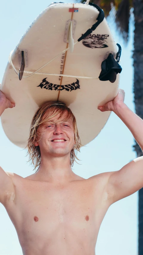 a man without a shirt standing under a surfboard on his head