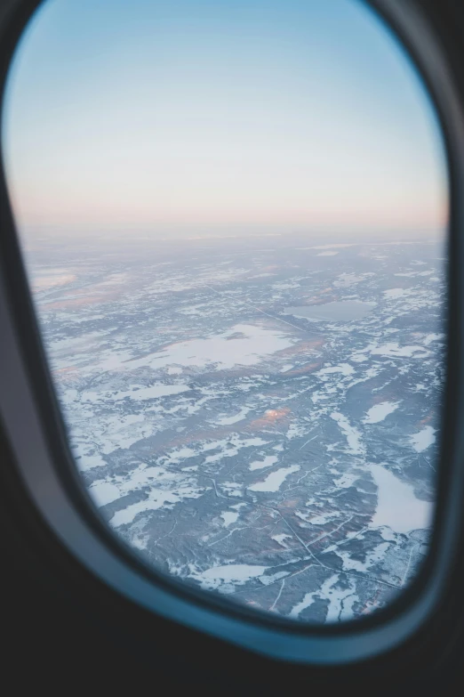 a po of an airplane flying over a city and snowy fields