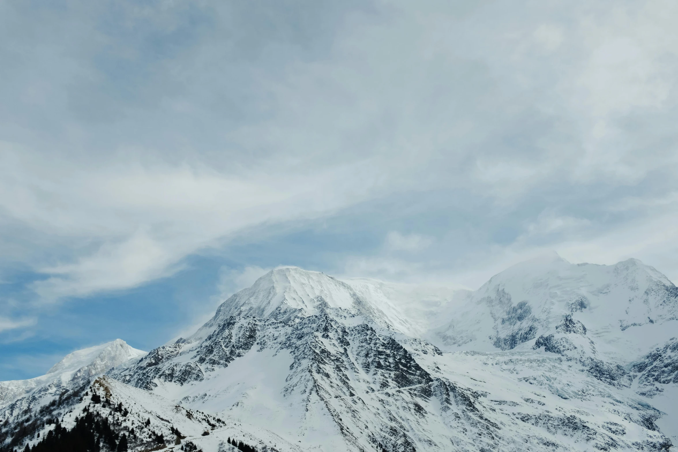 snow covered mountain tops and a cloudy sky