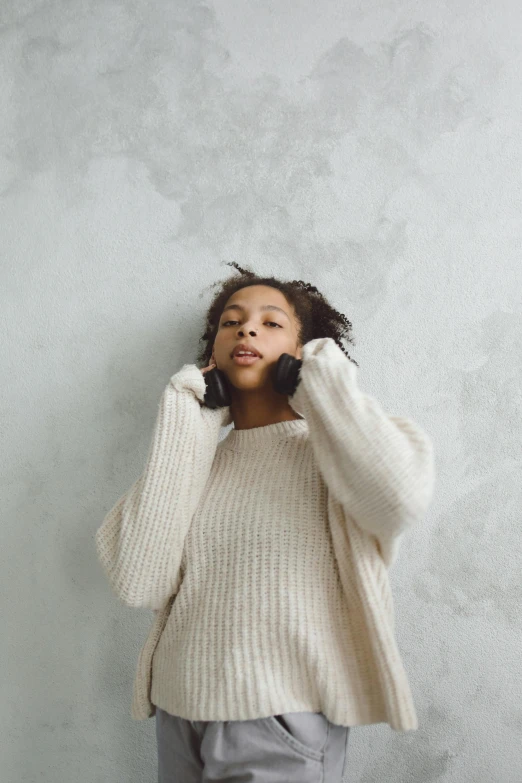 a girl wearing a white sweater and gray pants