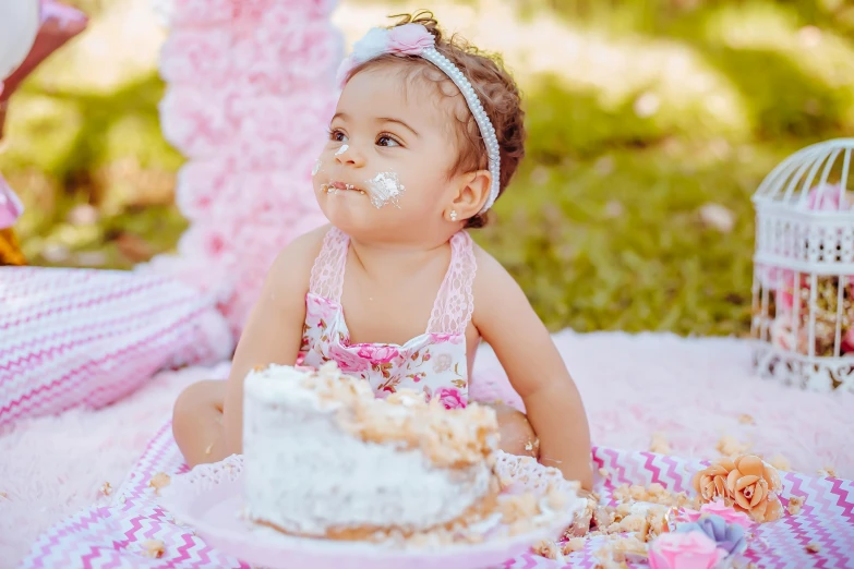 an infant girl in pink has a birthday cake