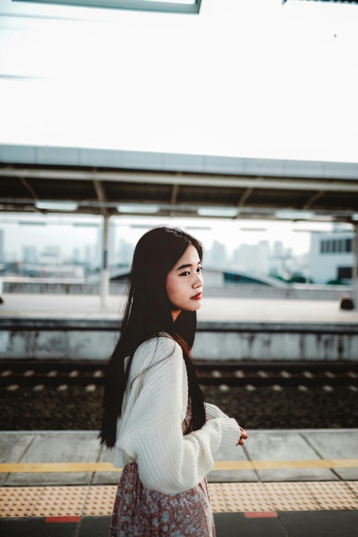 a woman is waiting at the station for her train to stop