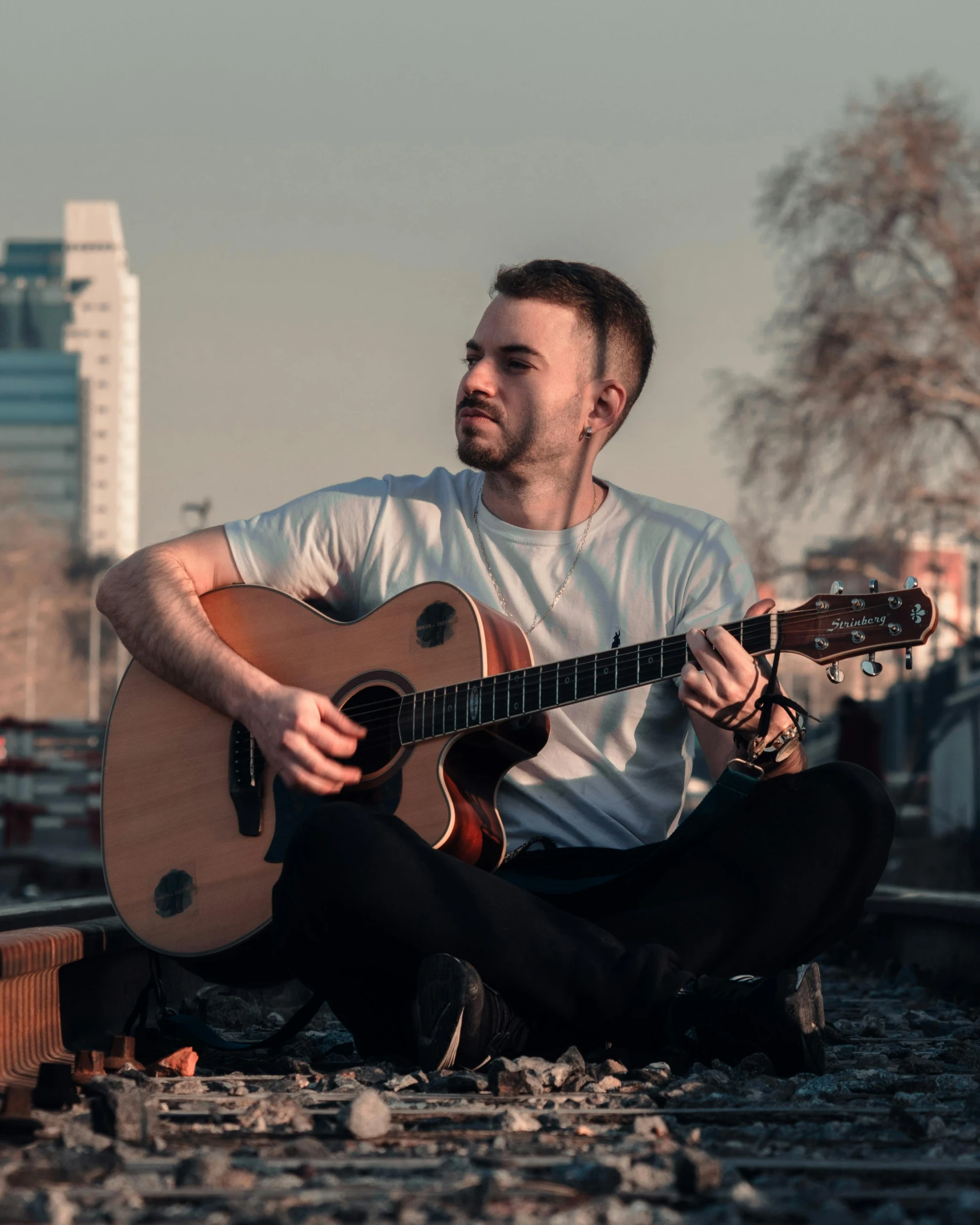 a man sitting on the train tracks playing his guitar