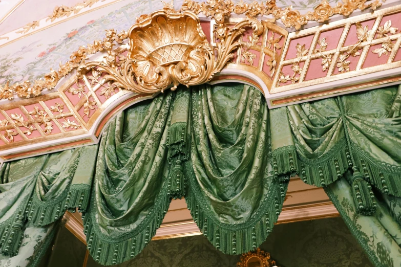 the ornate ceiling of a fancy room with green curtaining