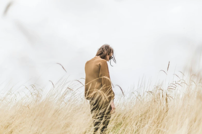 a man in tan shirt and pants walking through tall grass