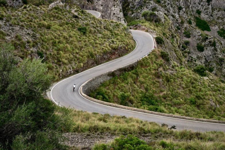 the cyclist is riding his bike on the curve in the hill side