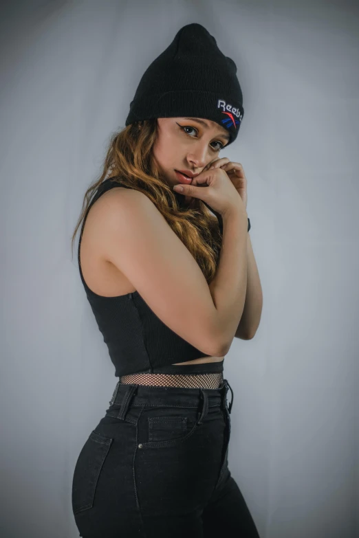 a girl poses wearing black clothing and a hat