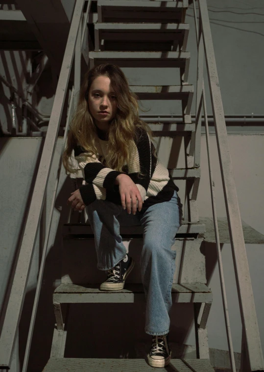 a girl in jeans is sitting on the stairs