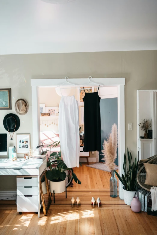 a room that has two windows and many clothes hanging on the clothes rack