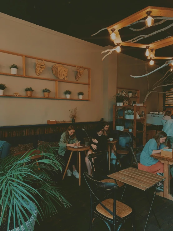 people are eating at restaurant tables next to potted plants