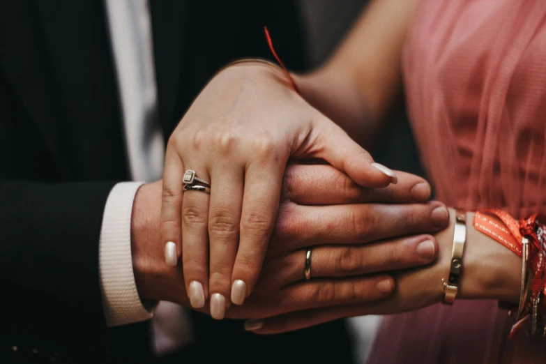 two people holding hands and a one has a gold ring