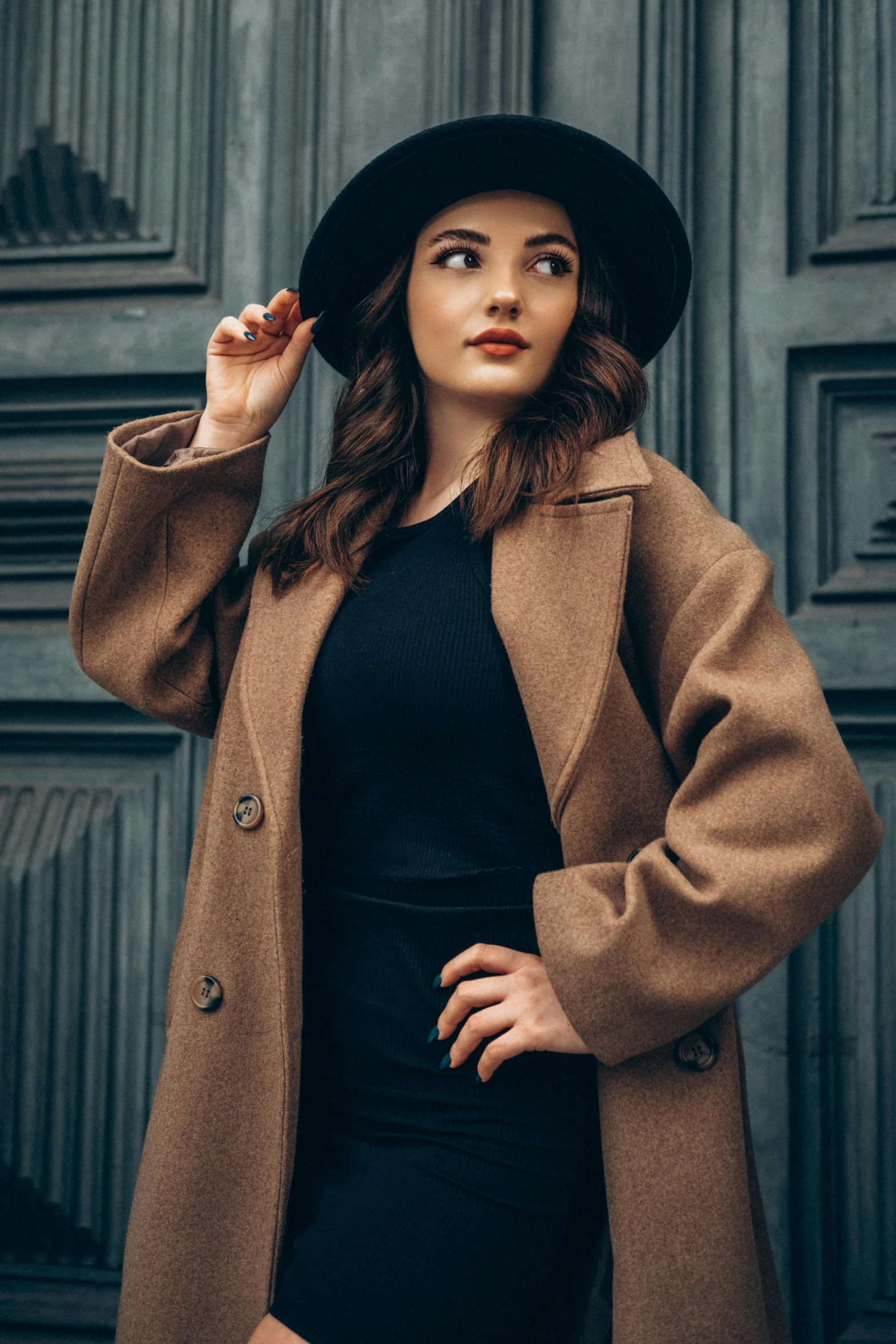 a girl with long brown hair wears a black dress and black hat