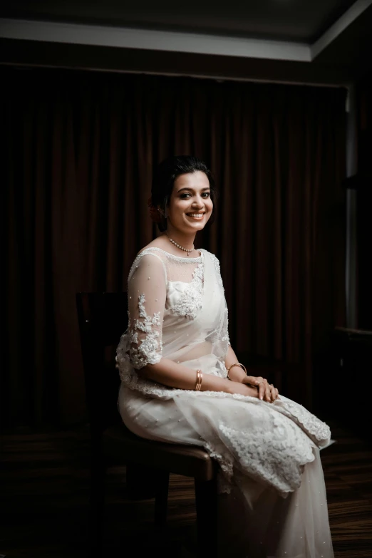 a smiling woman sitting in a chair in a darkened room