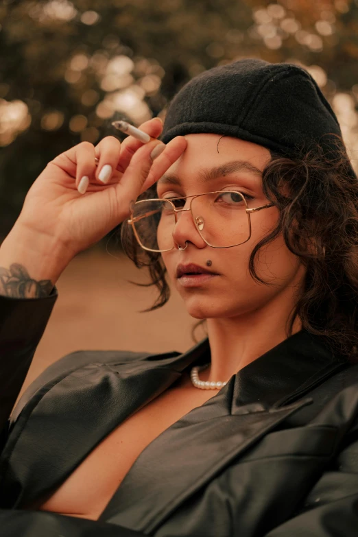 a girl in glasses and a beret holding a cigarette