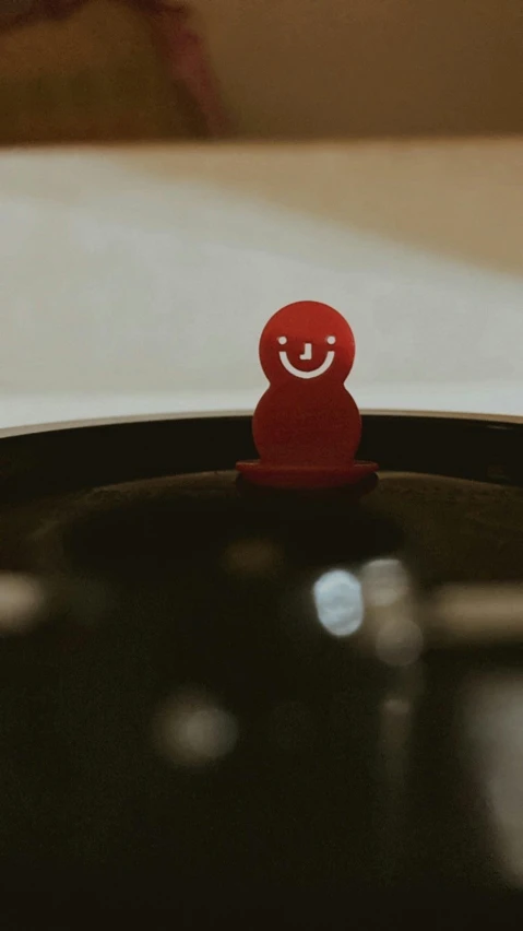 red smiley face toy standing in black vase