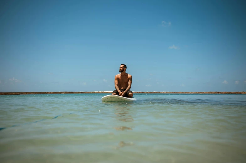 the man sits on the surfboard in calm water