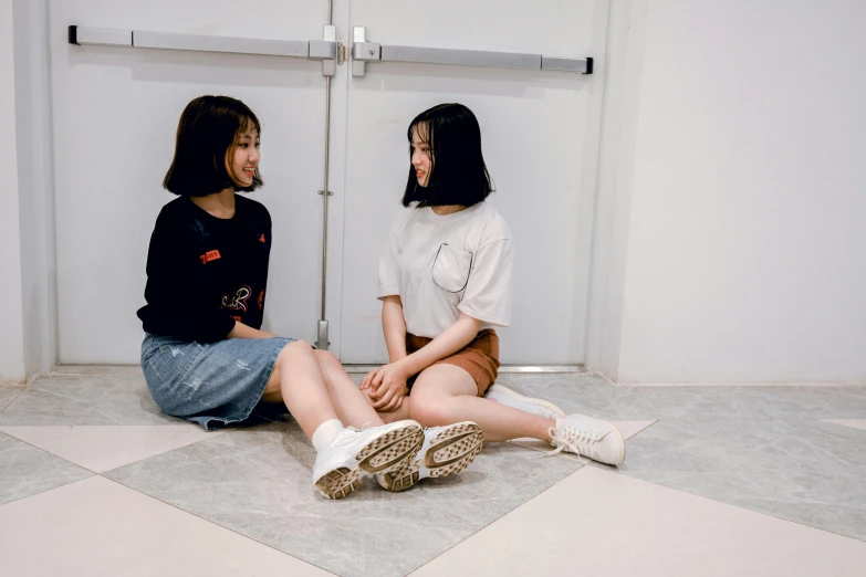 two woman sitting on the floor in the restroom