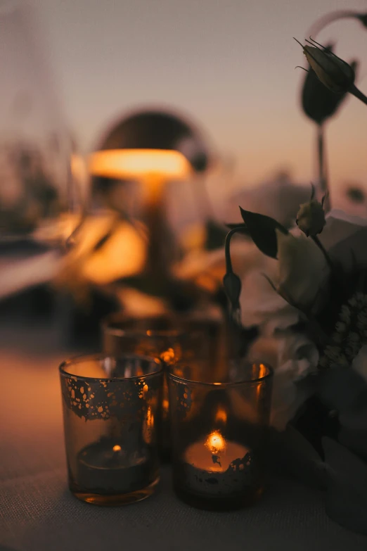 flowers are lit next to glass candles in front of a table