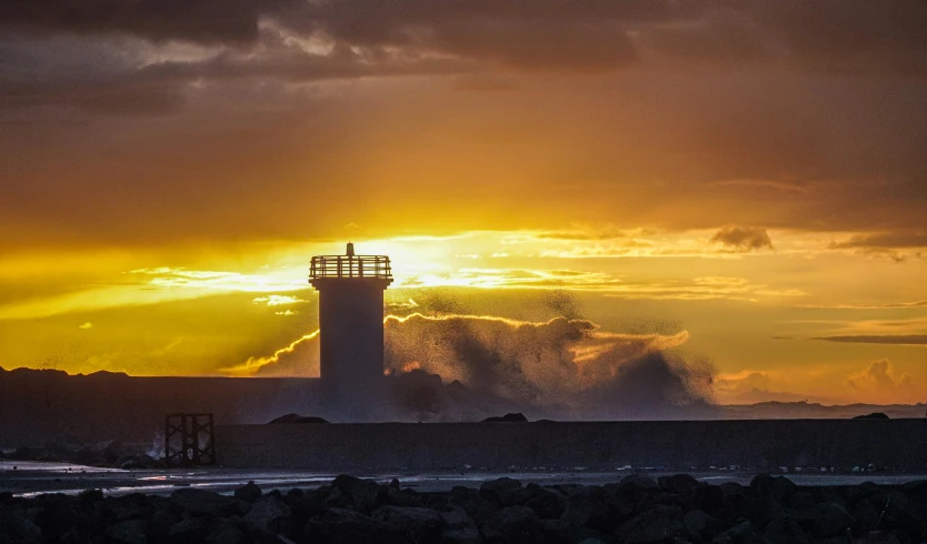 a tower sitting next to the ocean under a cloudy sky