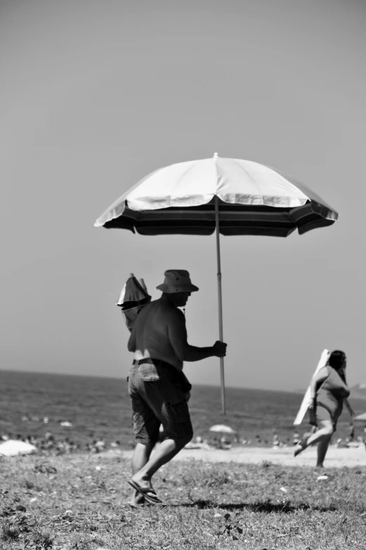 a man is carrying an umbrella as another man runs