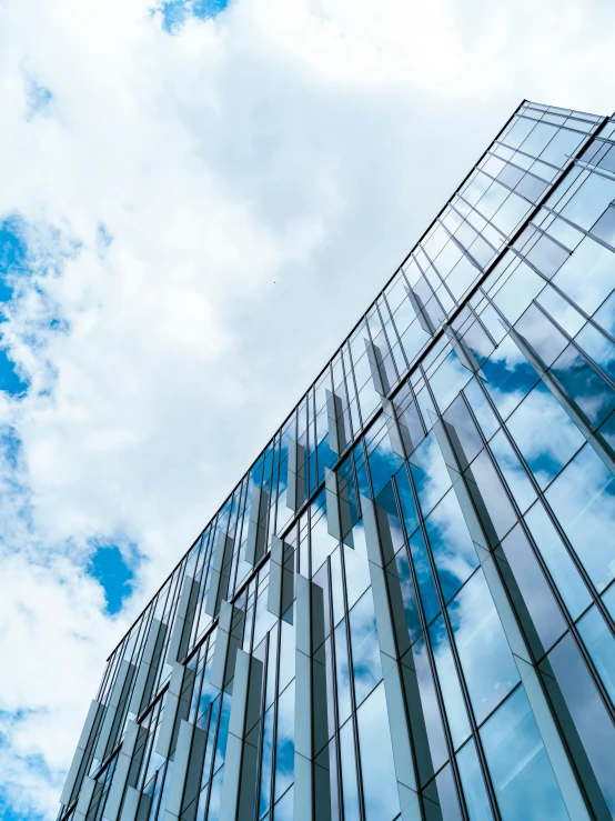 a glass building and blue sky with clouds