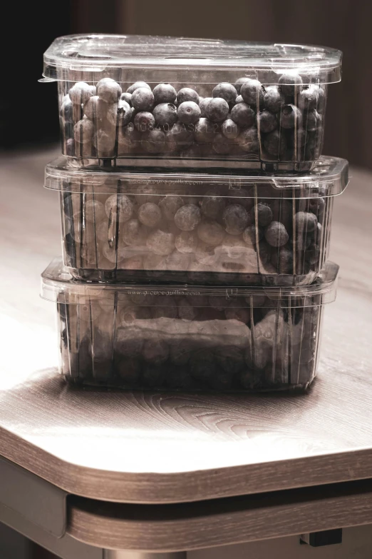 a wooden table topped with plastic containers filled with fruits