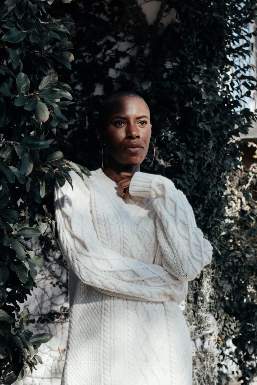 a woman in white clothes poses by bushes