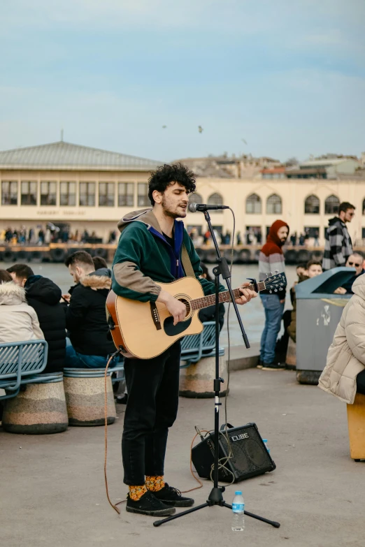 the young man is playing his guitar on the beach