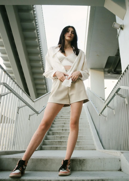 a woman wearing shorts and a jacket is leaning on some steps