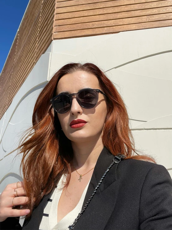 a young woman wearing sunglasses posing in front of a building