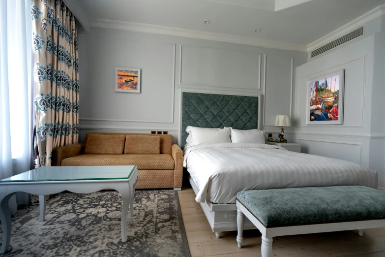 a clean, white bedroom has a blue headboard and footstool