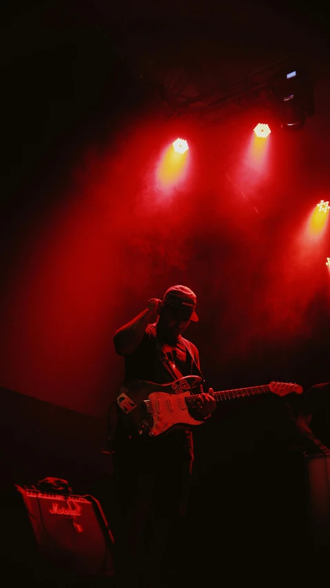 the man is playing guitar on stage at night