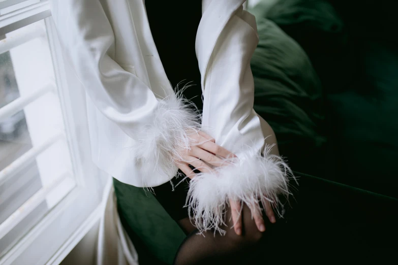 woman in white coat holding feathers by window