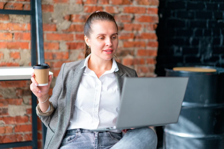 a woman holding a coffee cup and a laptop