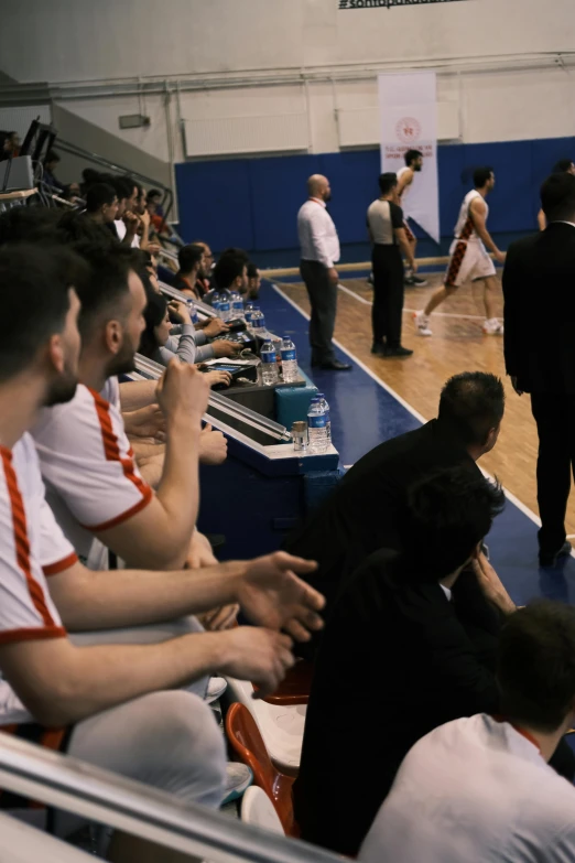 several men are sitting on the bleachers while talking