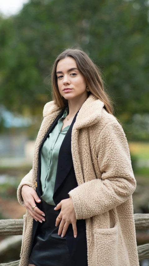 a woman standing next to a wooden fence