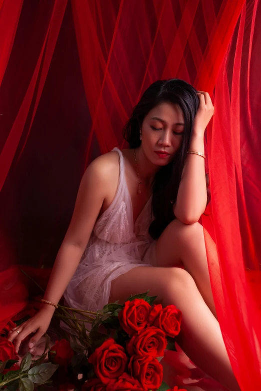 a beautiful woman with black hair sitting on a red bed