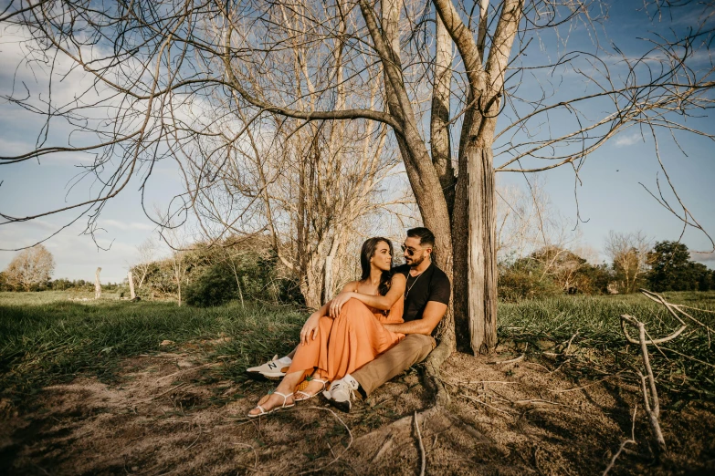 couple sitting under a large tree in the park