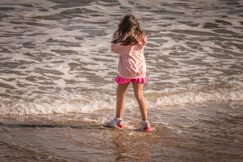 girl in the surf standing near the beach shore