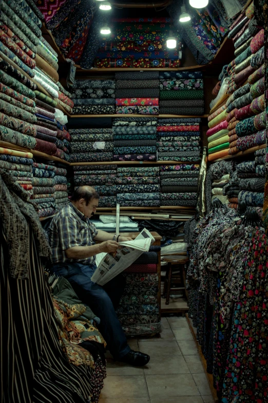 a man sitting on a chair reading a newspaper in a store