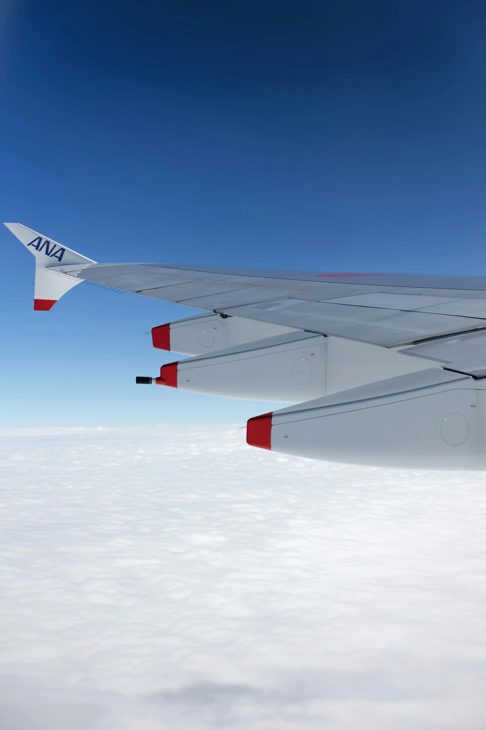 a airplane wing flying high over the clouds