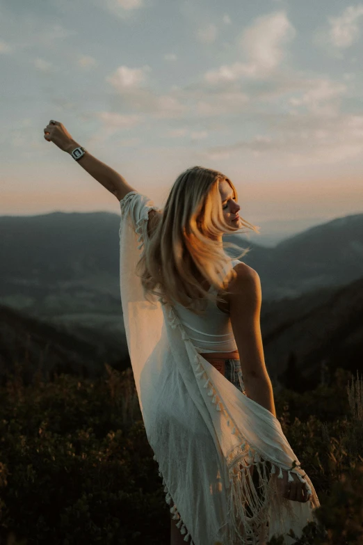 a woman in a white dress posing with her arms outstretched