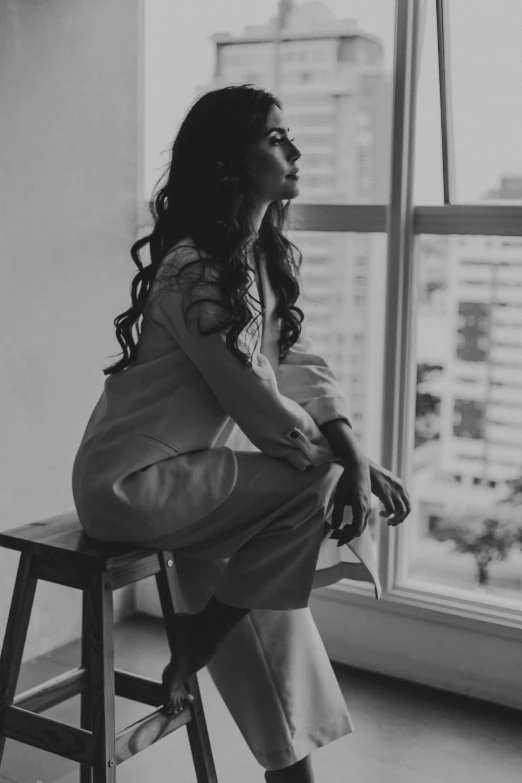 a woman is sitting down and looking outside a window